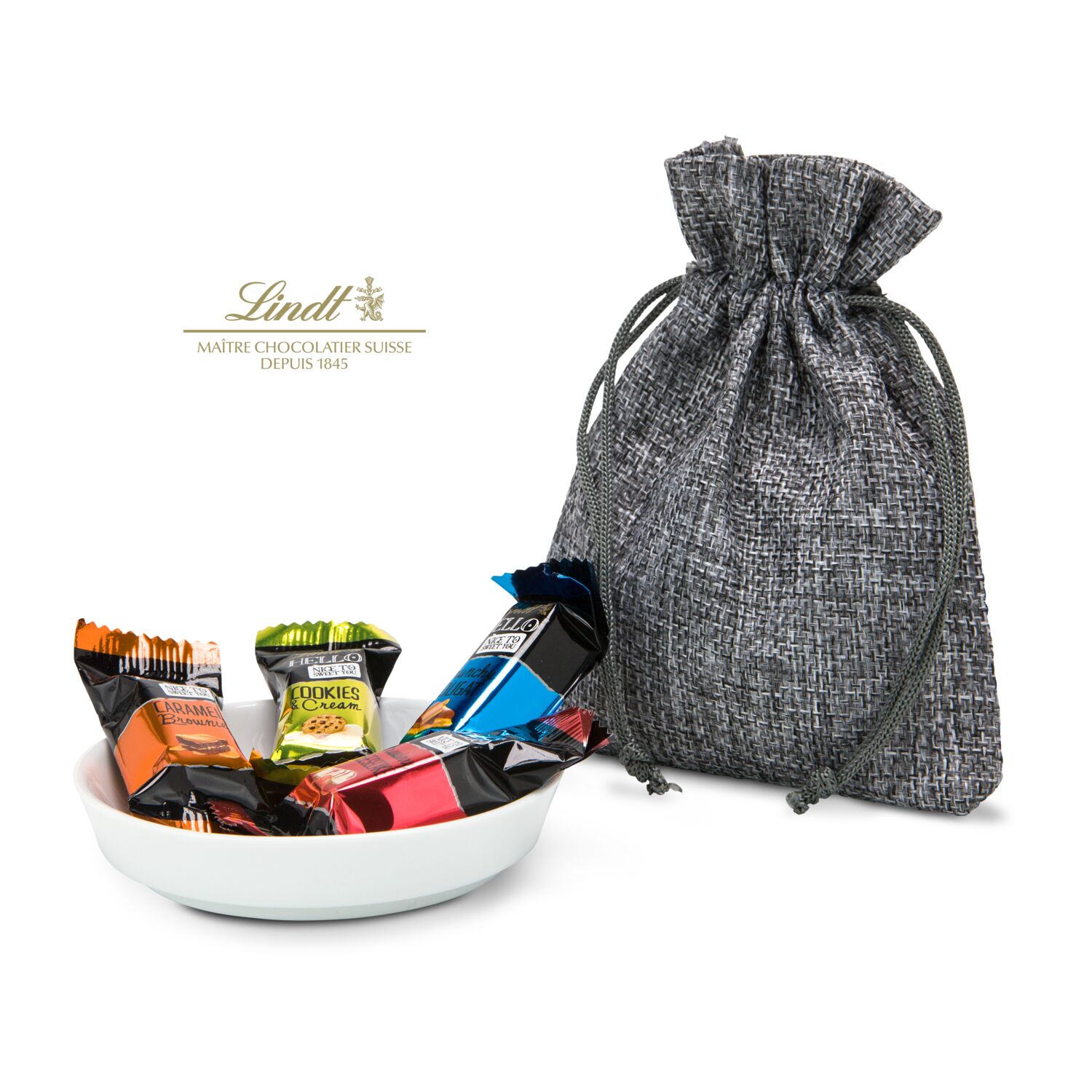 4 verschiedene Hello Schokoladen von Lindt (je 10 g) auf einem kleinen, modernen Servierteller aus Keramik. Verpackt im grauen Säckchen.